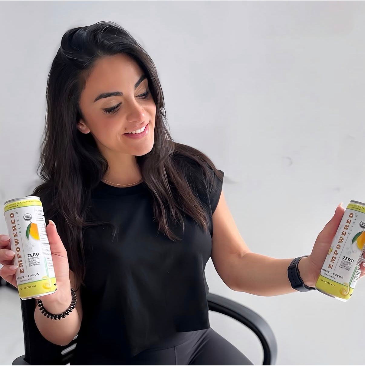 Stephanie Korour holding two cans of Empowered Elixir