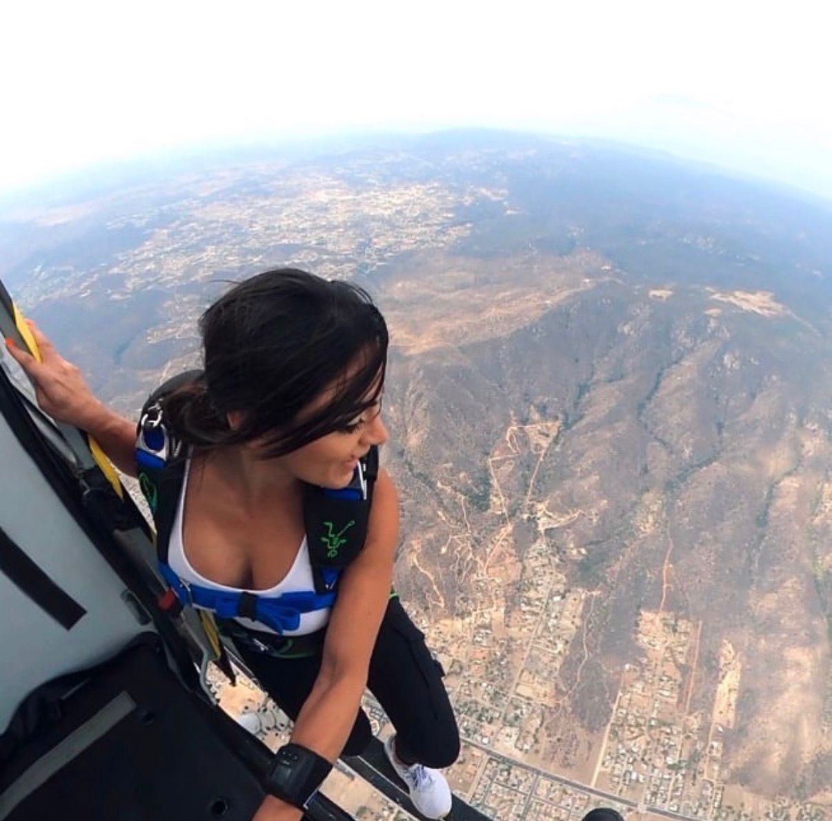 Stephanie Korour skydiving over a coastal mountain range
