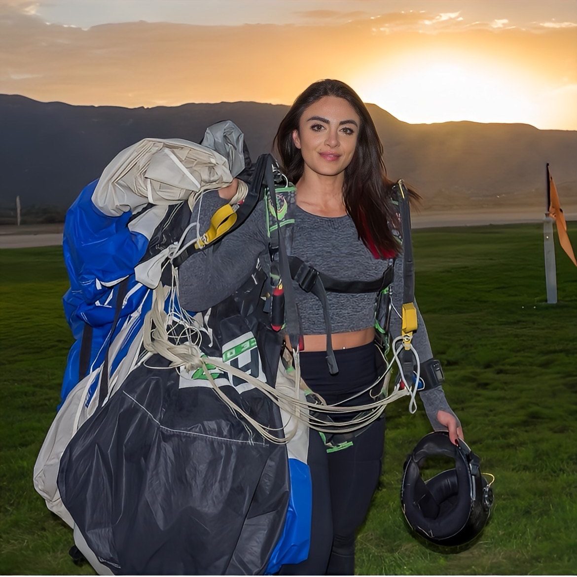 Empowered Elixir founder after a sunset skydive, holding her parachute and helmet